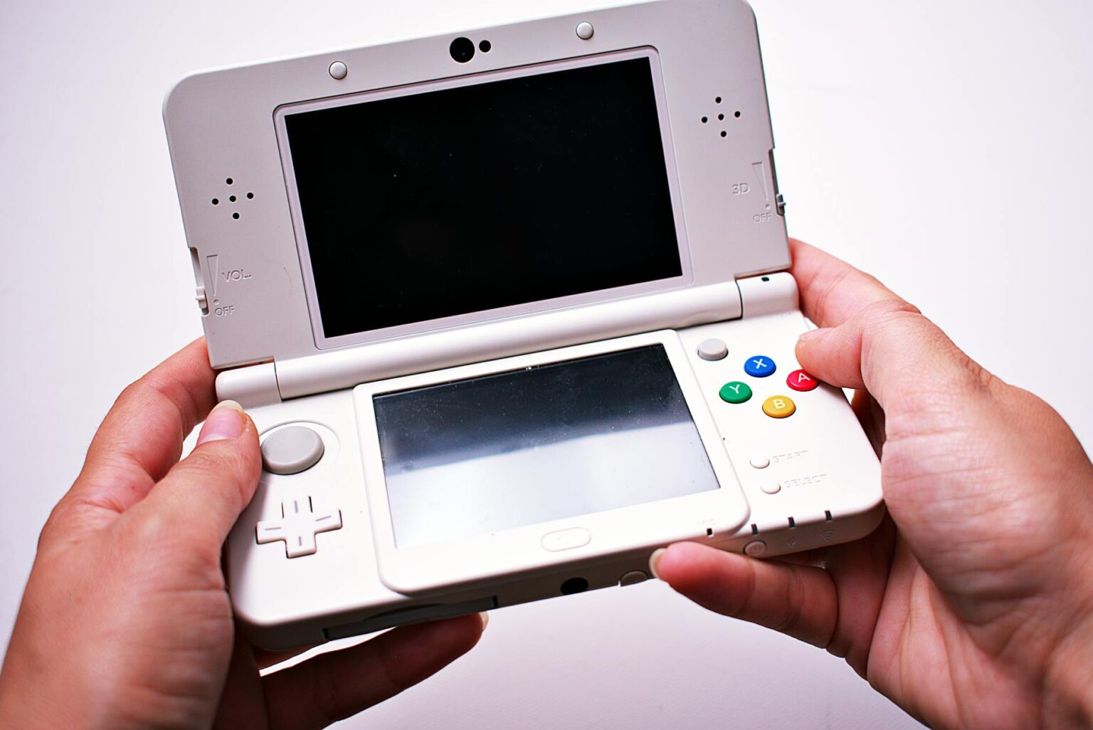 Person holding a portable gaming device with screen displaying a video game