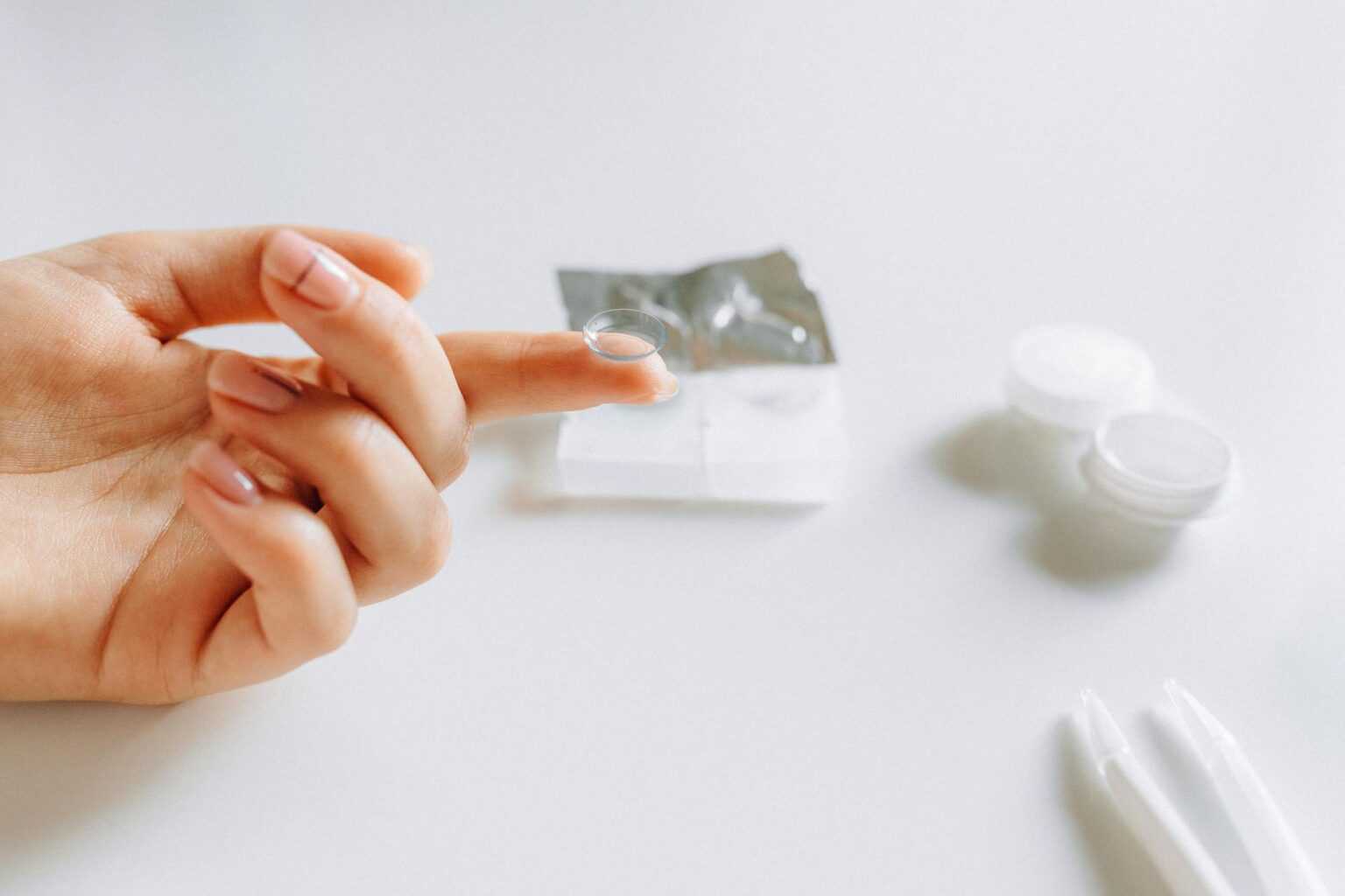 Close-up of a person's eye with a contact lens being inserted, showing the delicate nature of eye-worn technology