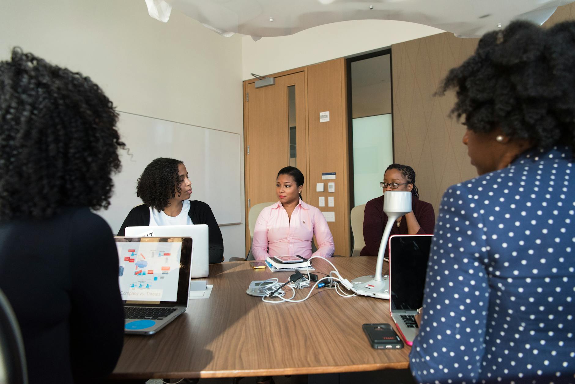 Business professionals collaborating with mobile devices in conference room
