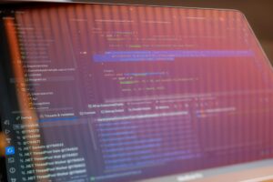 Software developer working on code at computer with multiple monitors showing programming interfaces