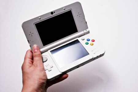 Person holding portable gaming device with screen displaying game interface