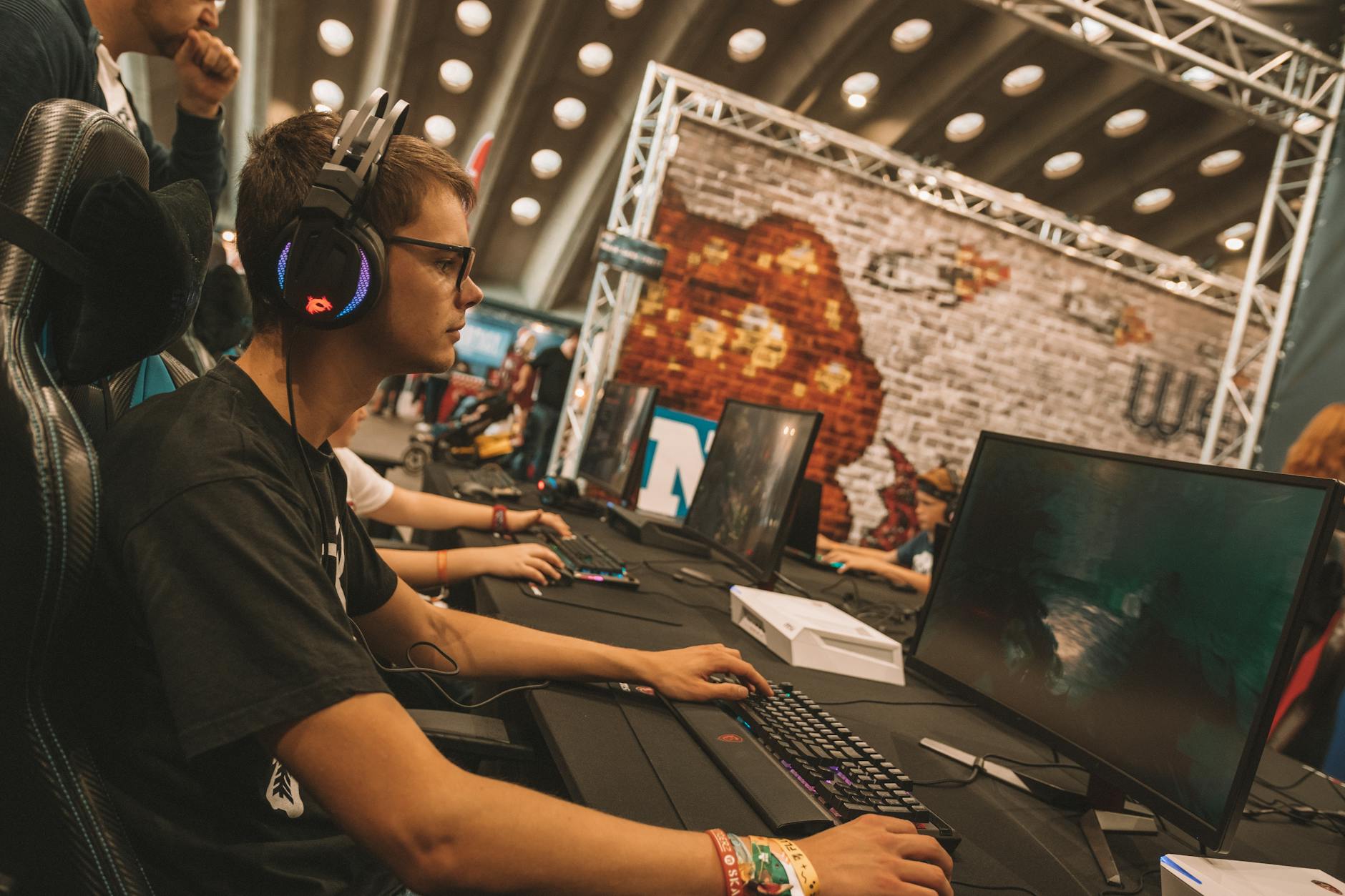 A competitive esports arena with players at stations and screens displaying gameplay