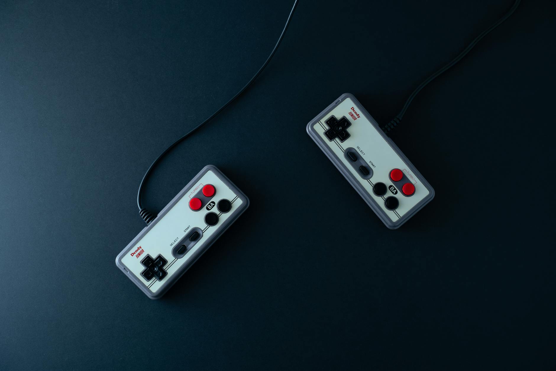 Close-up of a game controller resting near a monitor showing a first-person shooter game