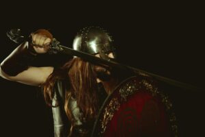 A lone warrior in dark armor standing in a shadowy fantasy landscape