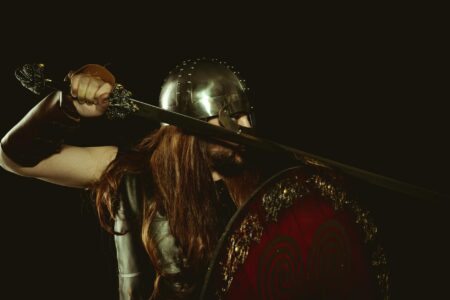A lone warrior in dark armor standing in a shadowy fantasy landscape