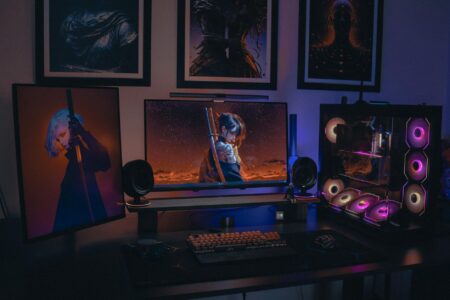 A gaming PC setup with multiple monitors displaying a colorful open-world survival game environment