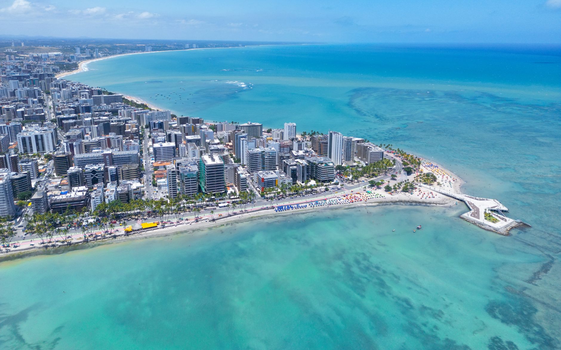 Aerial view of a tropical coastal city with palm trees and blue water