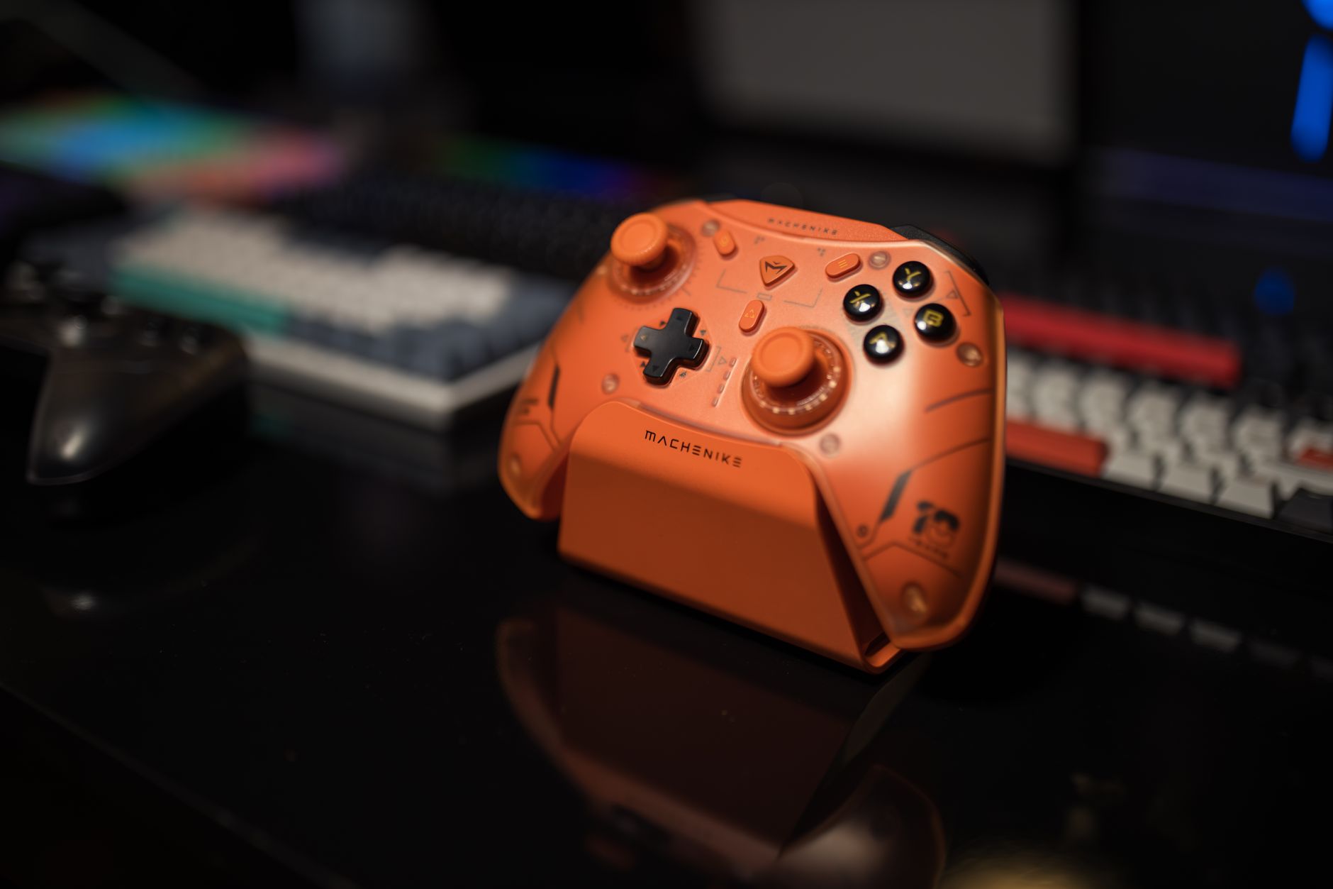 A gaming controller resting in front of a desktop PC monitor in a dimly lit room