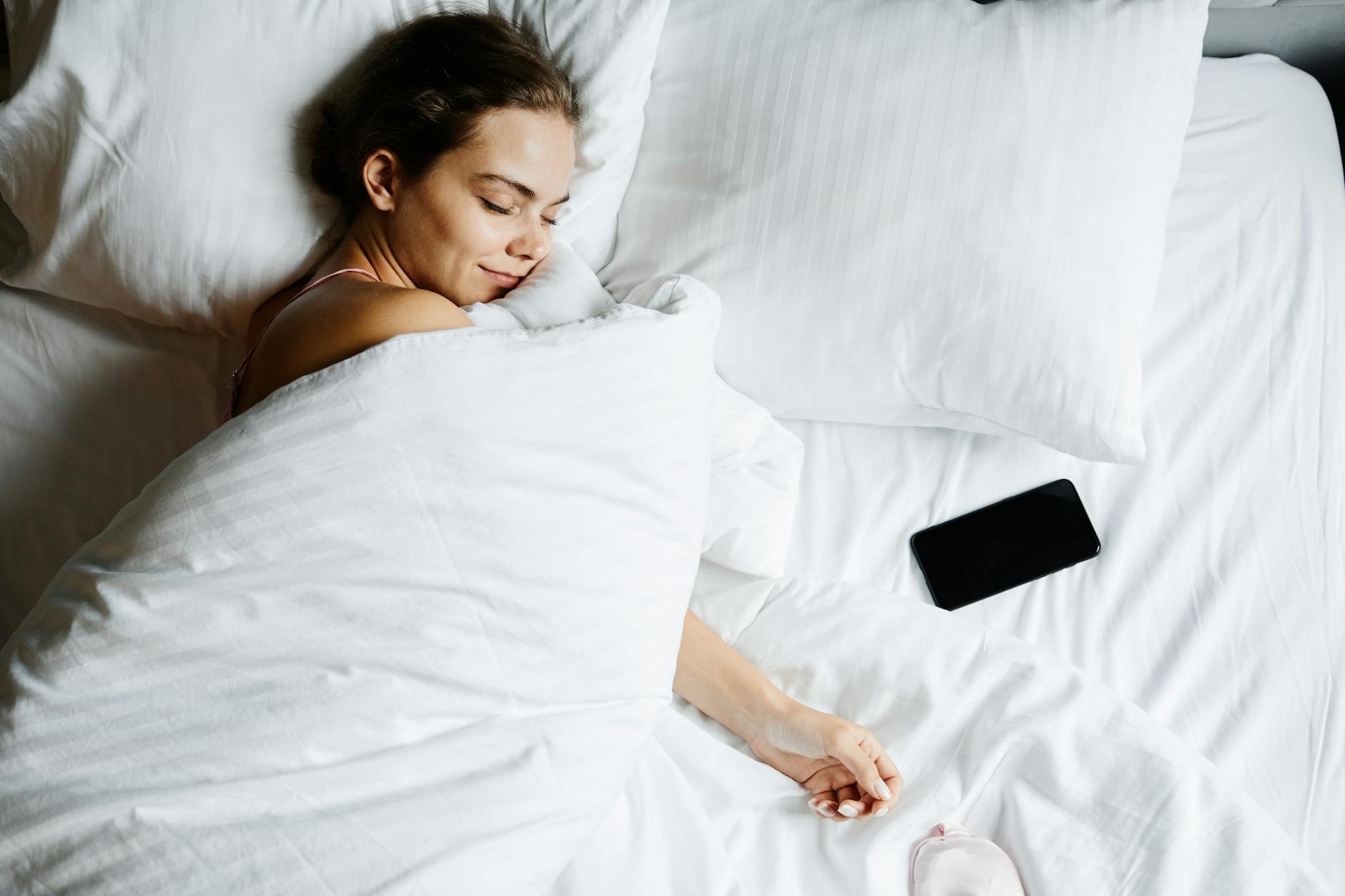 A person sleeping in bed with soft morning light coming through the window