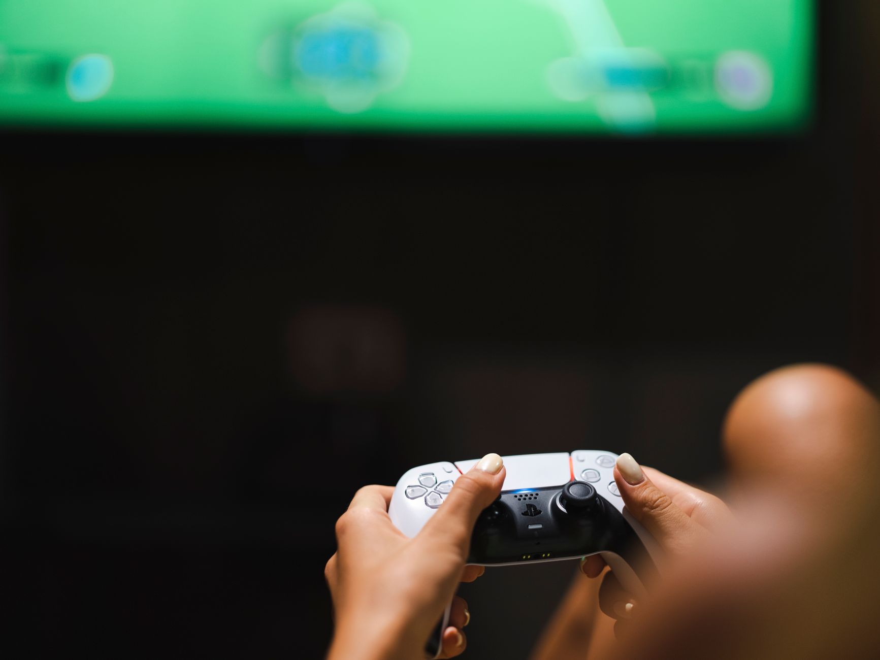 A person playing a video game on a console controller in a dimly lit room