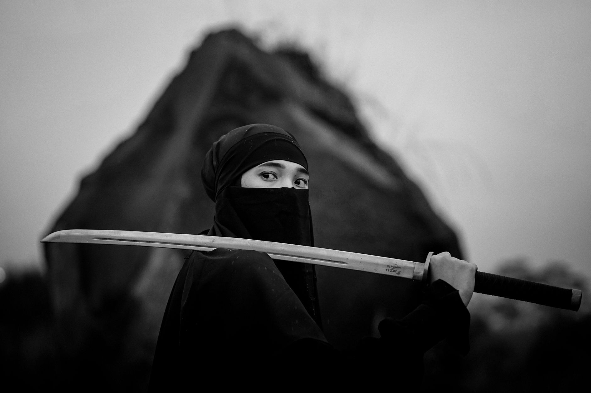 Silhouette of a figure holding a sword against a dramatic sky, representing samurai game aesthetics