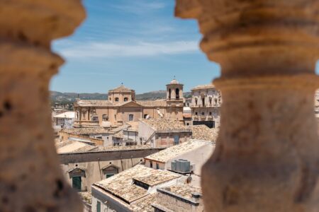 Sunlit Sicilian countryside with historic stone architecture, evoking early 20th century atmosphere