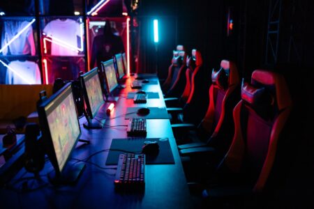 A gaming PC setup with glowing keyboard and monitor displaying a dark fantasy game interface