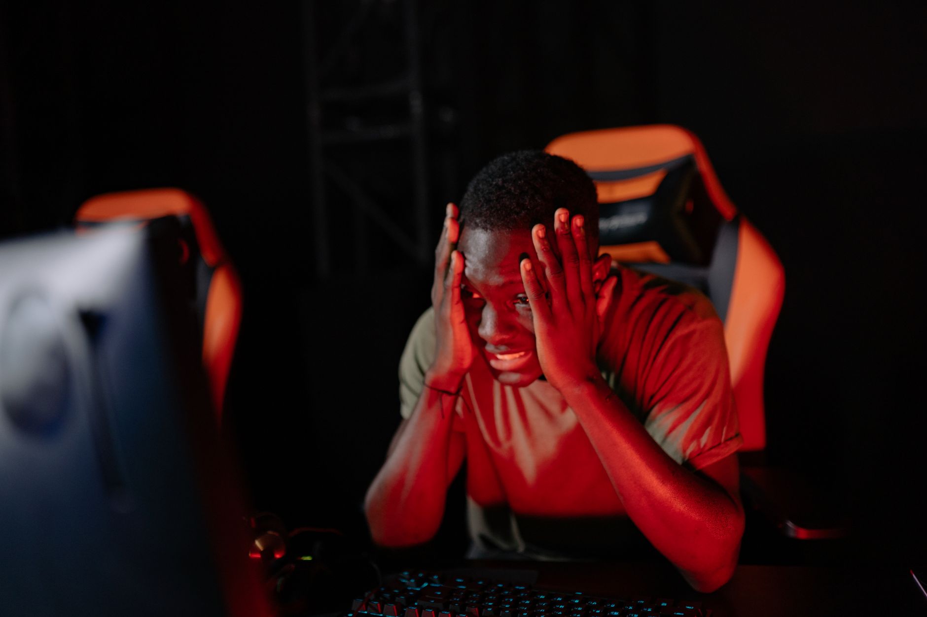 A person sitting at a desk looking frustrated while playing a video game on a computer