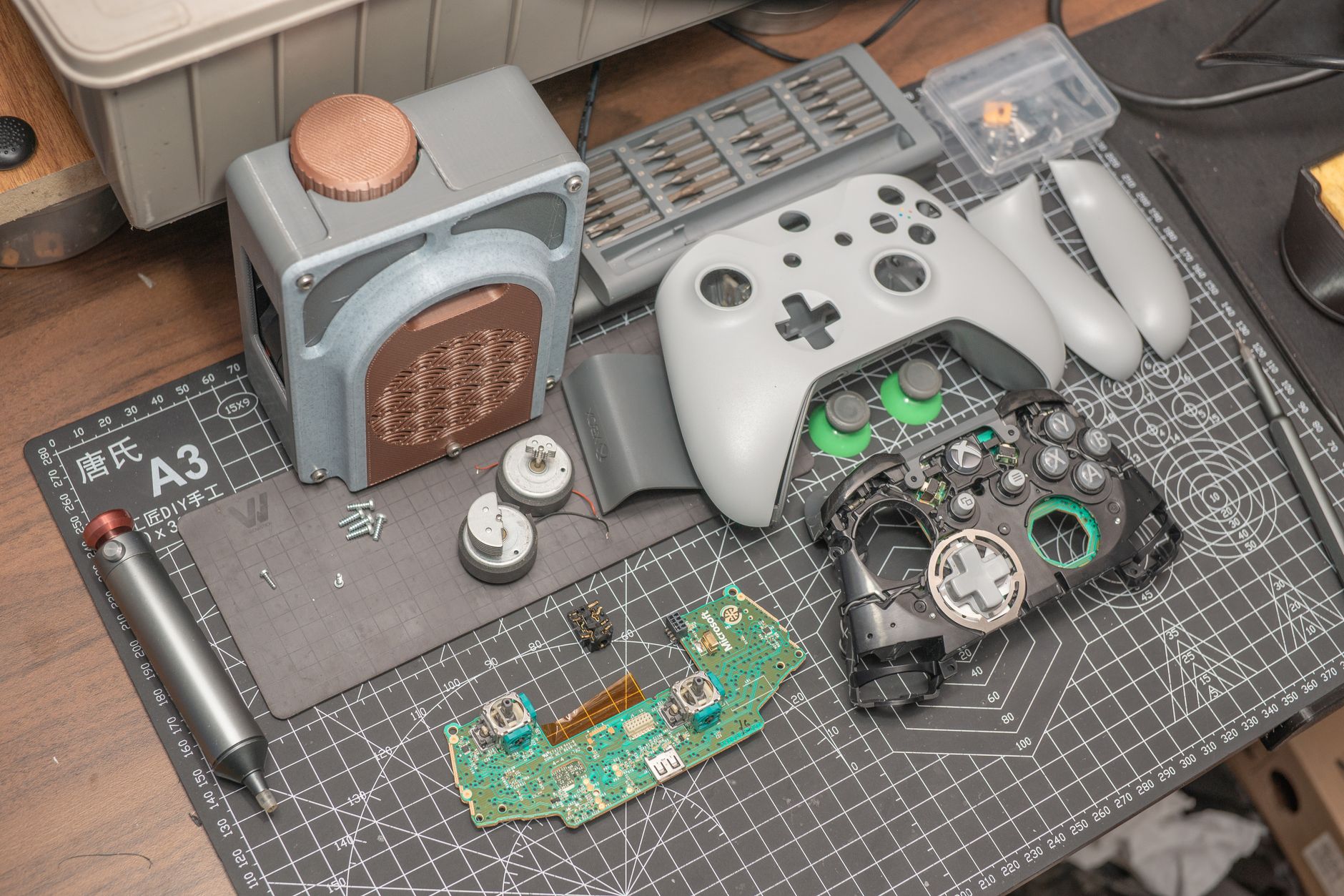 A gaming controller resting on a desk beside a monitor showing a dark fantasy game world