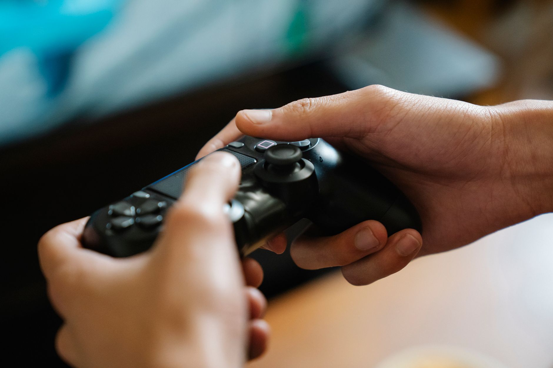 A person playing a video game on a console controller in a dimly lit room