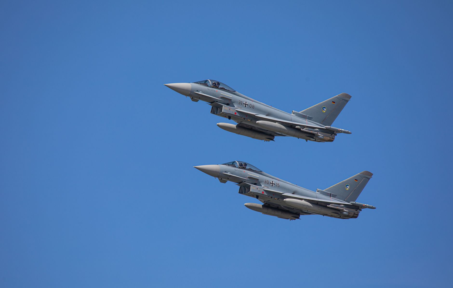 A fighter jet flying at high altitude against a clear blue sky