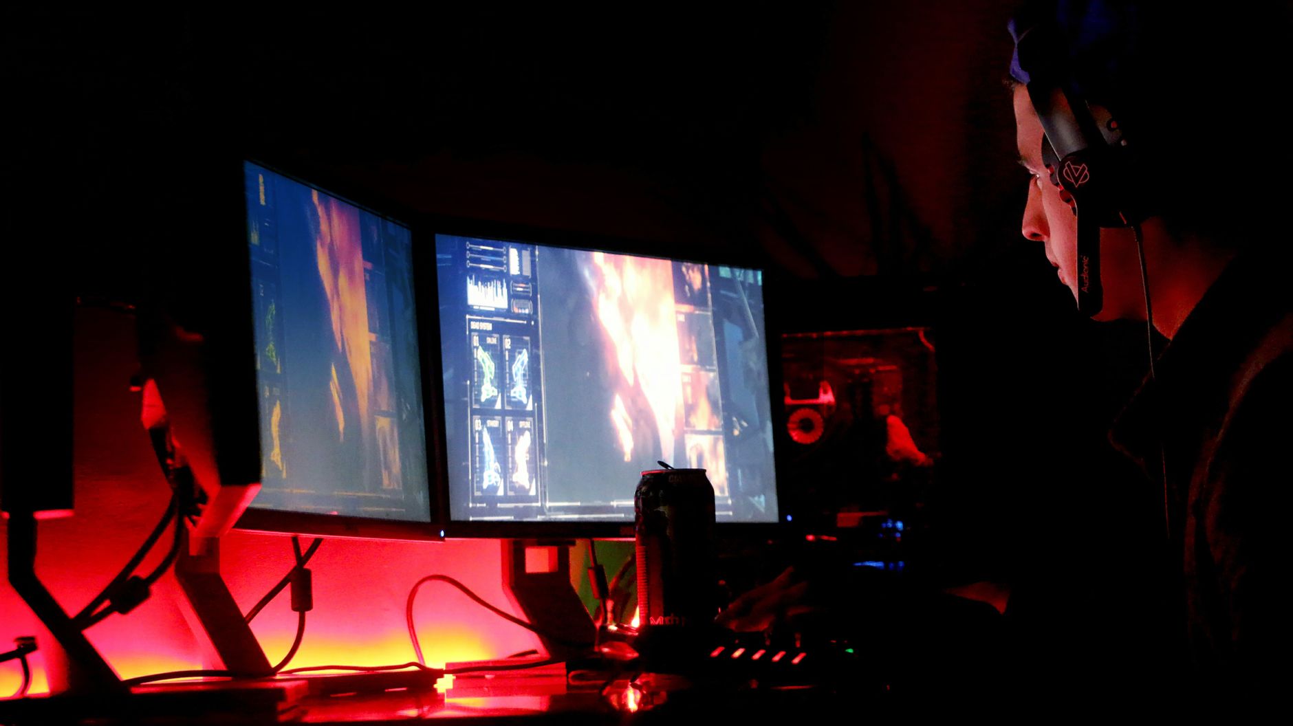 Player gaming in a darkened room, illuminated by a monitor screen