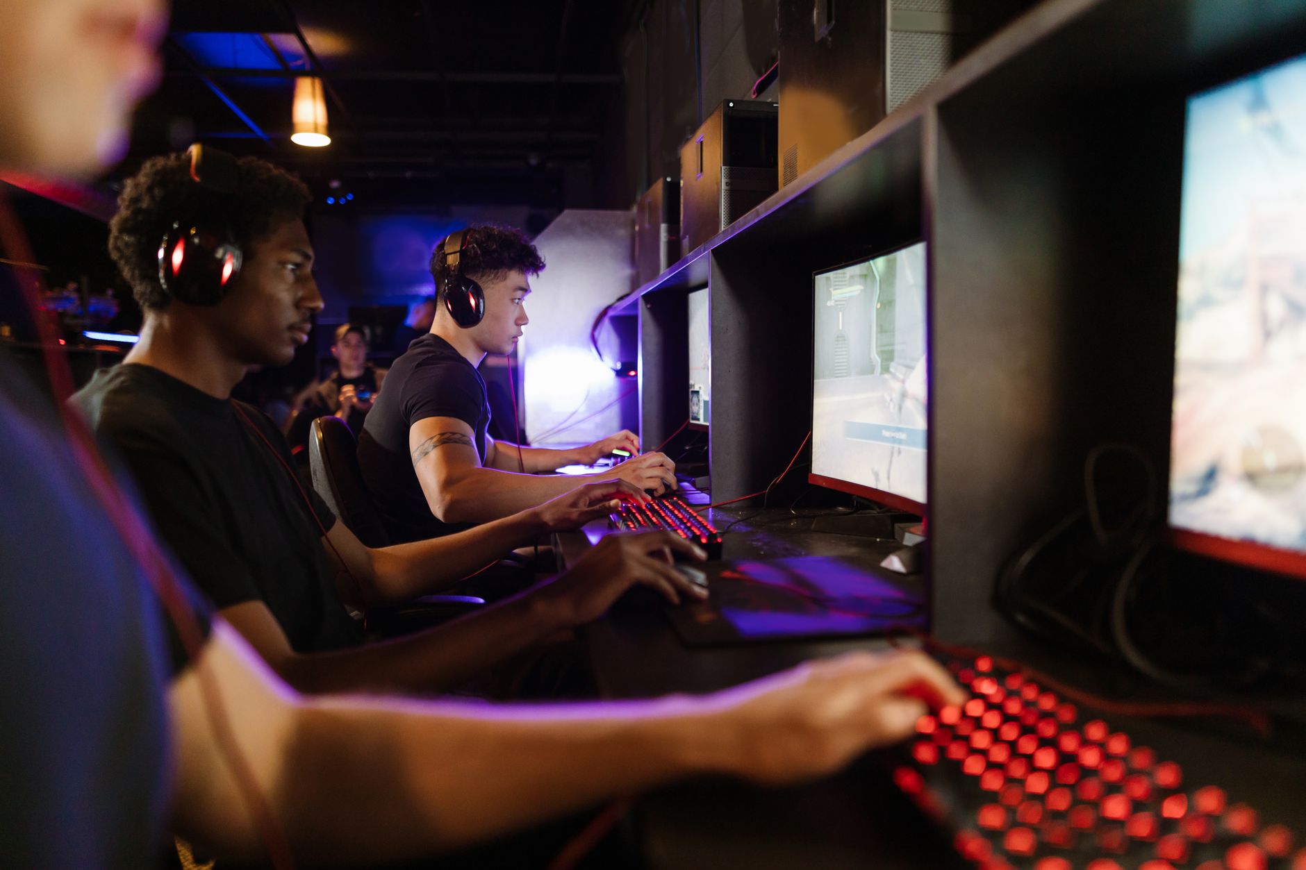 Player seated at a gaming desk with monitor illuminated in a dark room